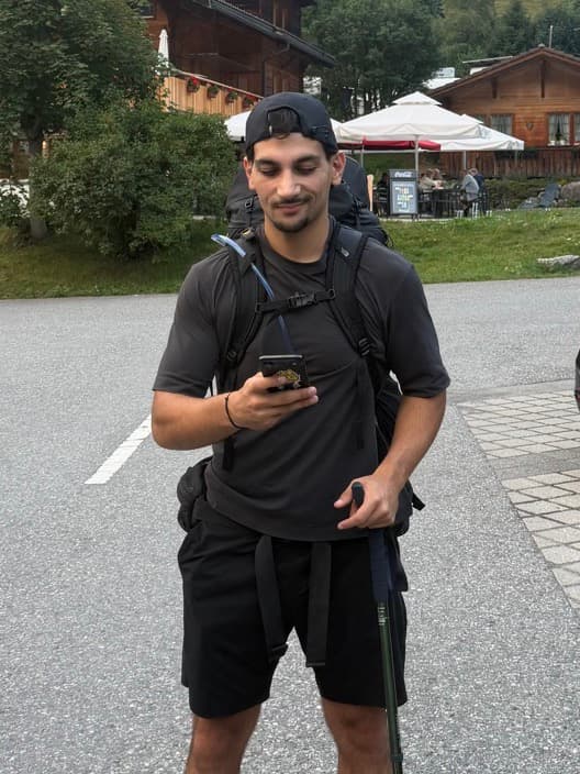 Furkan at 80 kg, hiking with a backpack and poles, phone in hand.